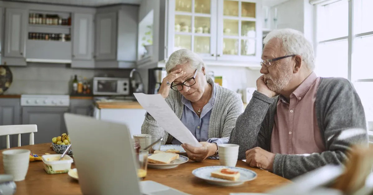 A couple in South Burnett looking concerned while reading an electricity bill at the kitchen table.